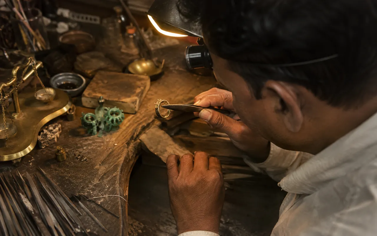 A jeweller at his bench inspecting a gold ring